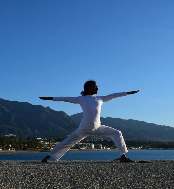 Person doing a gentle stretching yoga pose outdoors at sunrise.